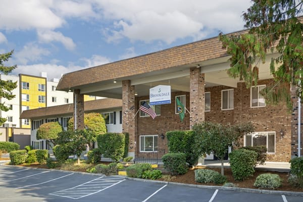 A two-story hotel building with a large entrance and parking area.