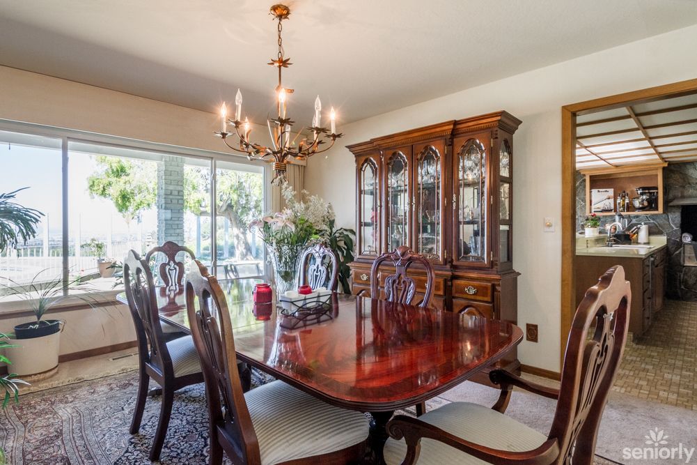 An elegantly decorated dining room featuring a wooden table, chairs, a chandelier, and a large cabinet.