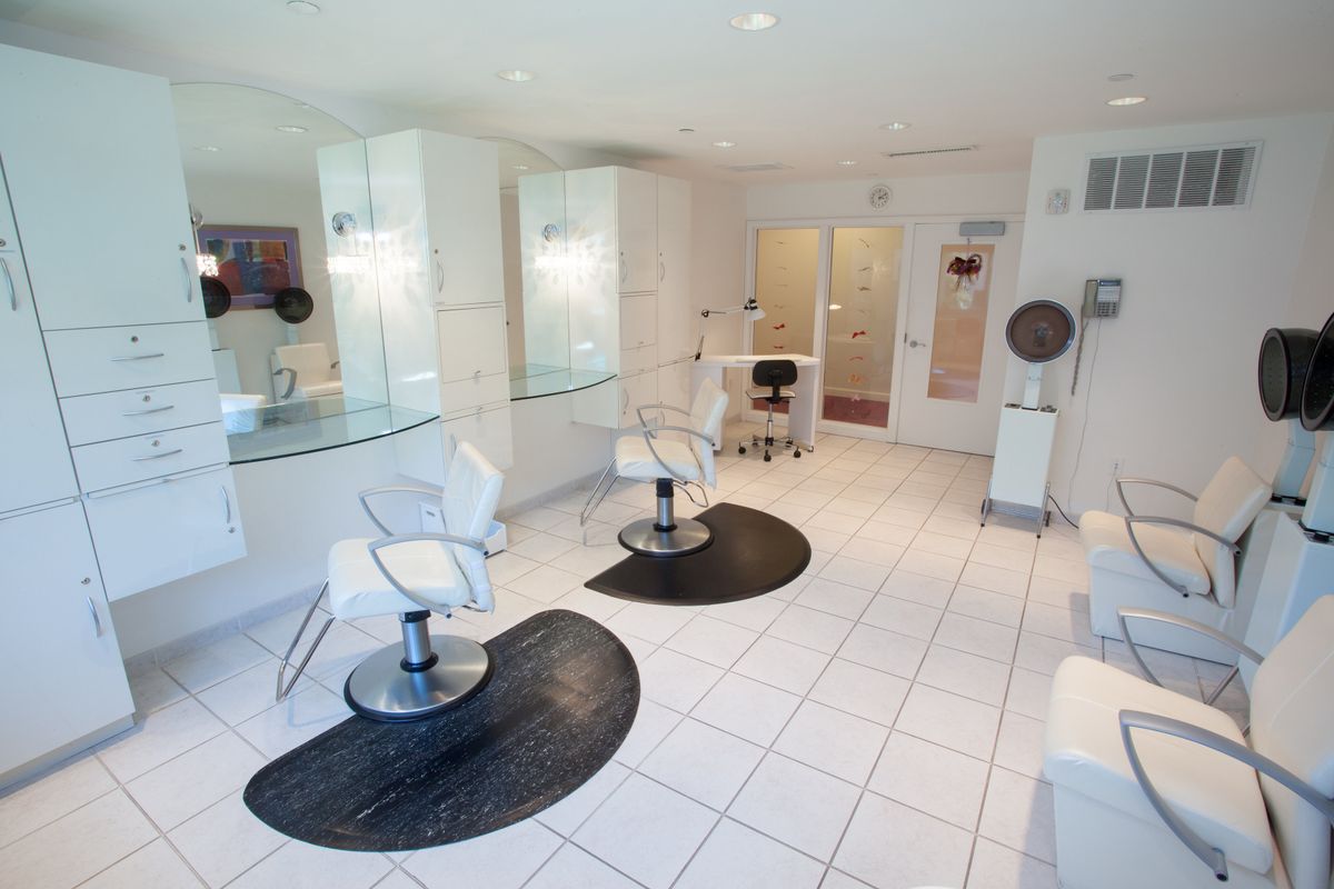 A modern hair salon with white tiles and stylish chairs.