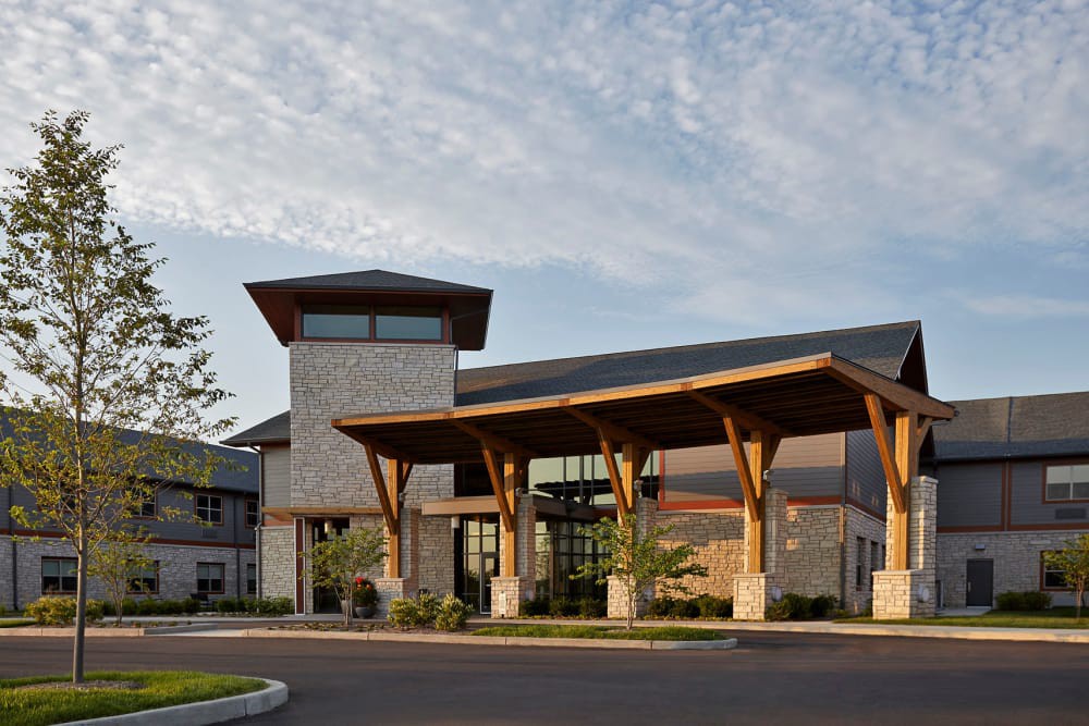 A modern building with prominent wooden beams and large windows, featuring an inviting entrance.