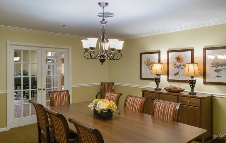 A well-decorated dining room with a large table, elegant chairs, and a chandelier overhead.