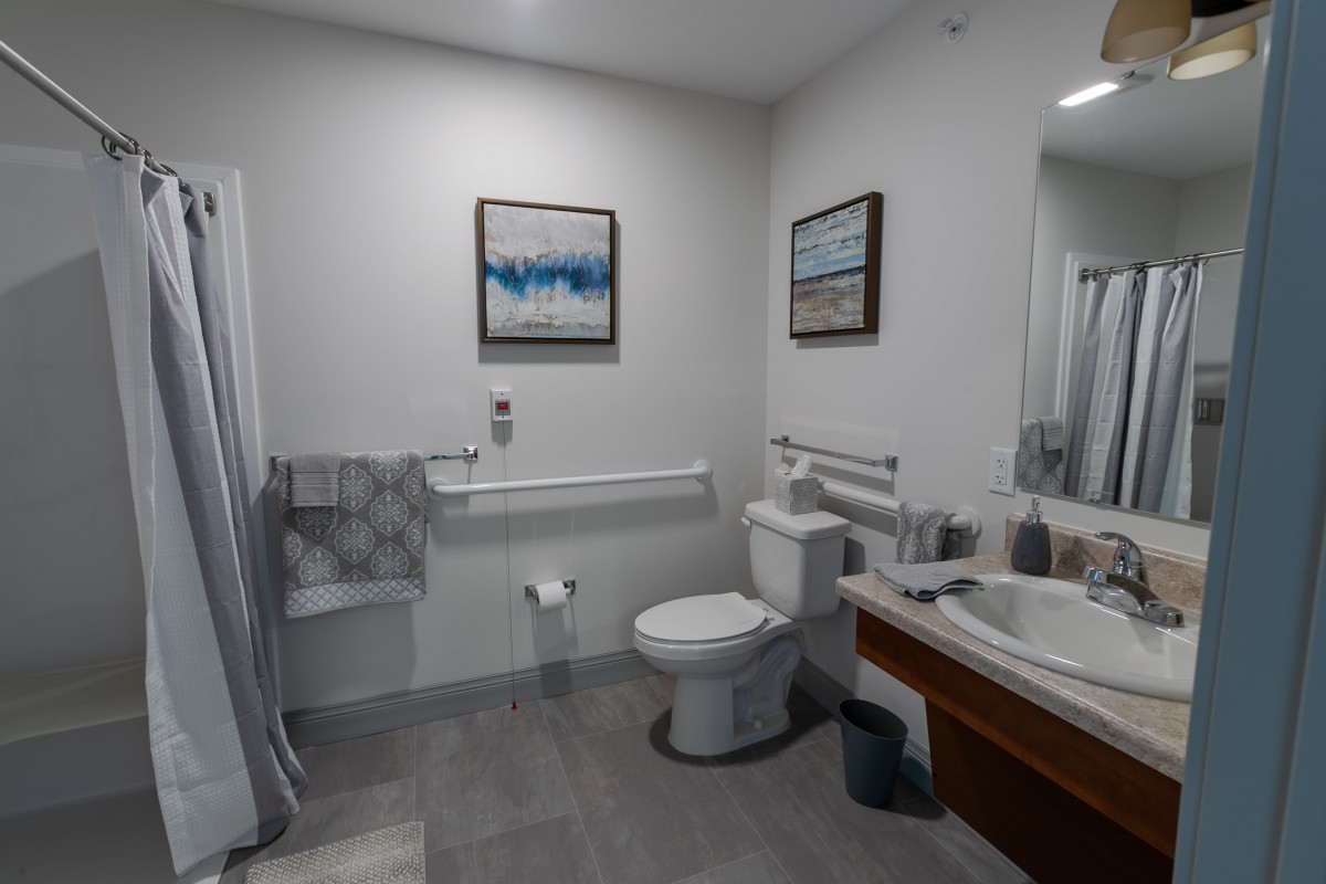 A modern bathroom featuring a toilet, sink, mirror, and decorative paintings.