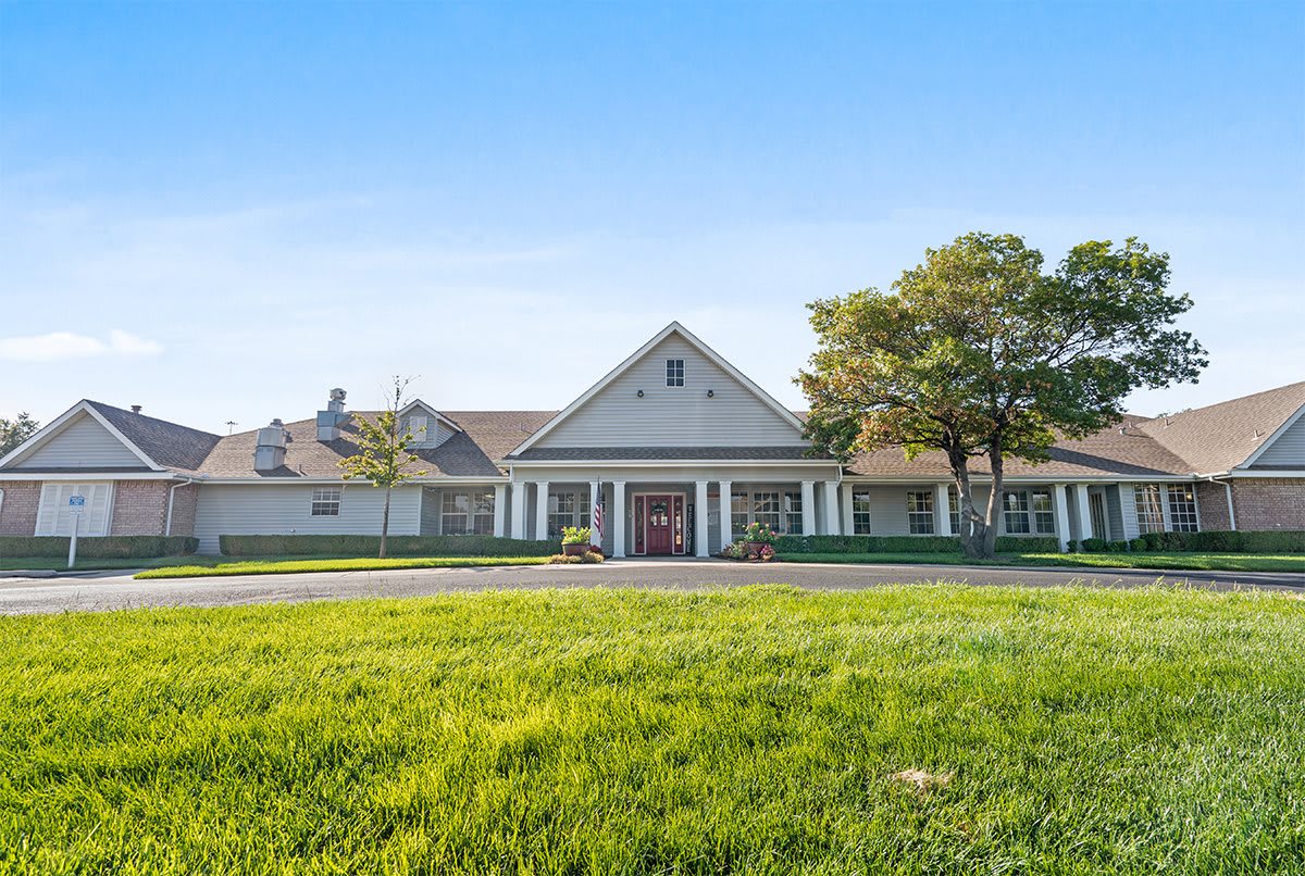 A large residential house with a neatly trimmed lawn and clear blue sky.