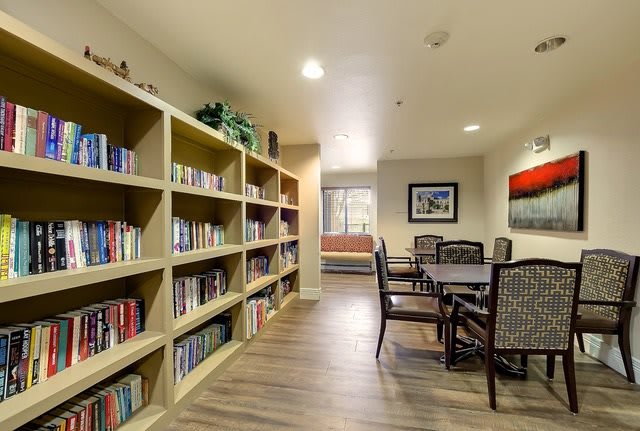 A cozy library with bookshelves and a reading area featuring tables and chairs.