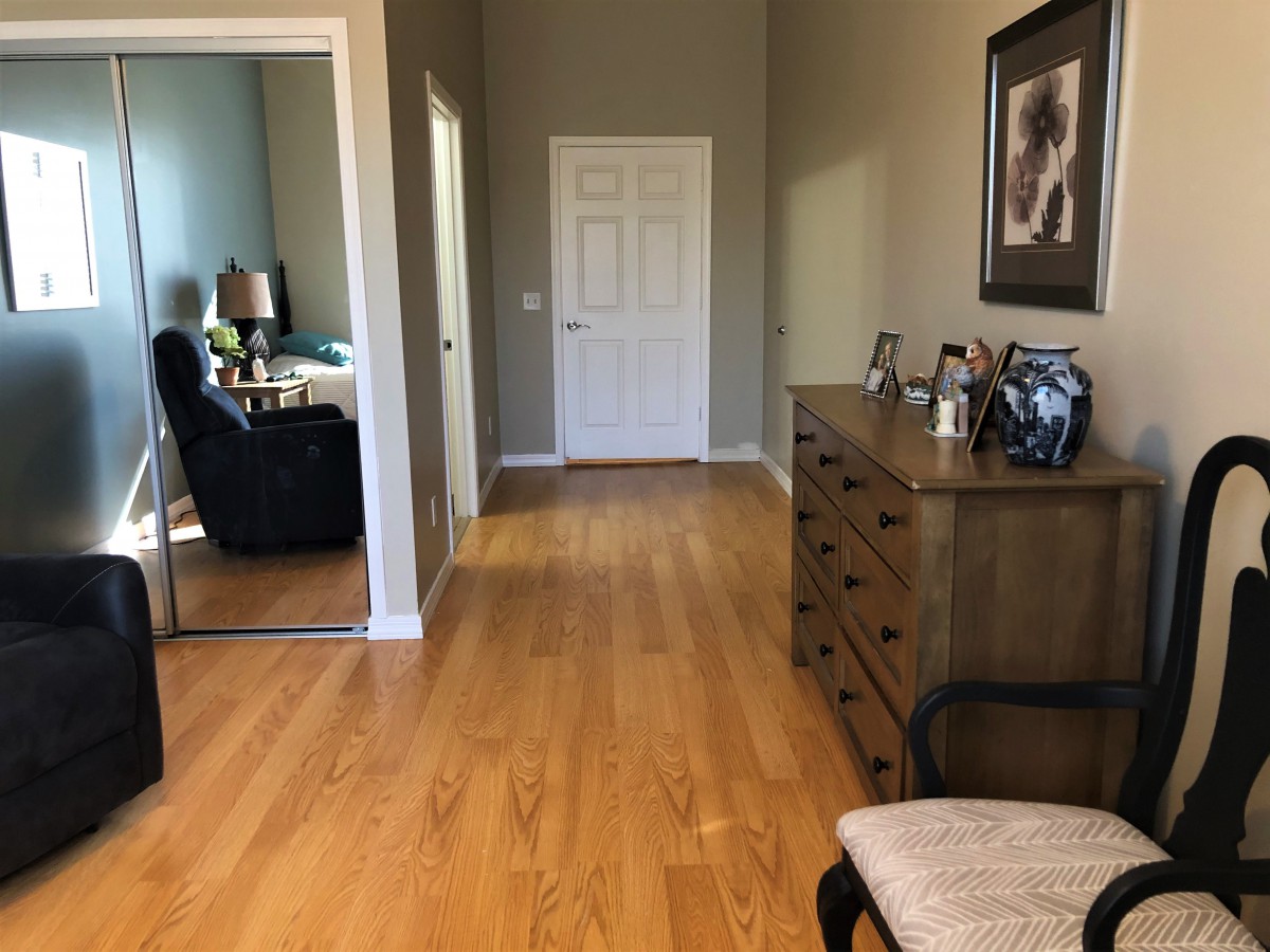 A cozy hallway with a wooden floor and a dresser, leading to another room.