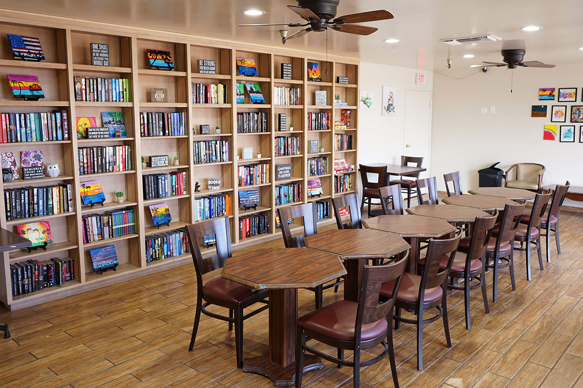 A cozy library with wooden bookshelves and a large table surrounded by chairs.