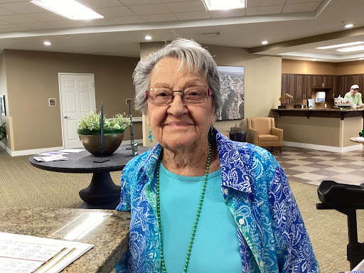 An elderly woman smiling warmly in a cozy indoor setting.
