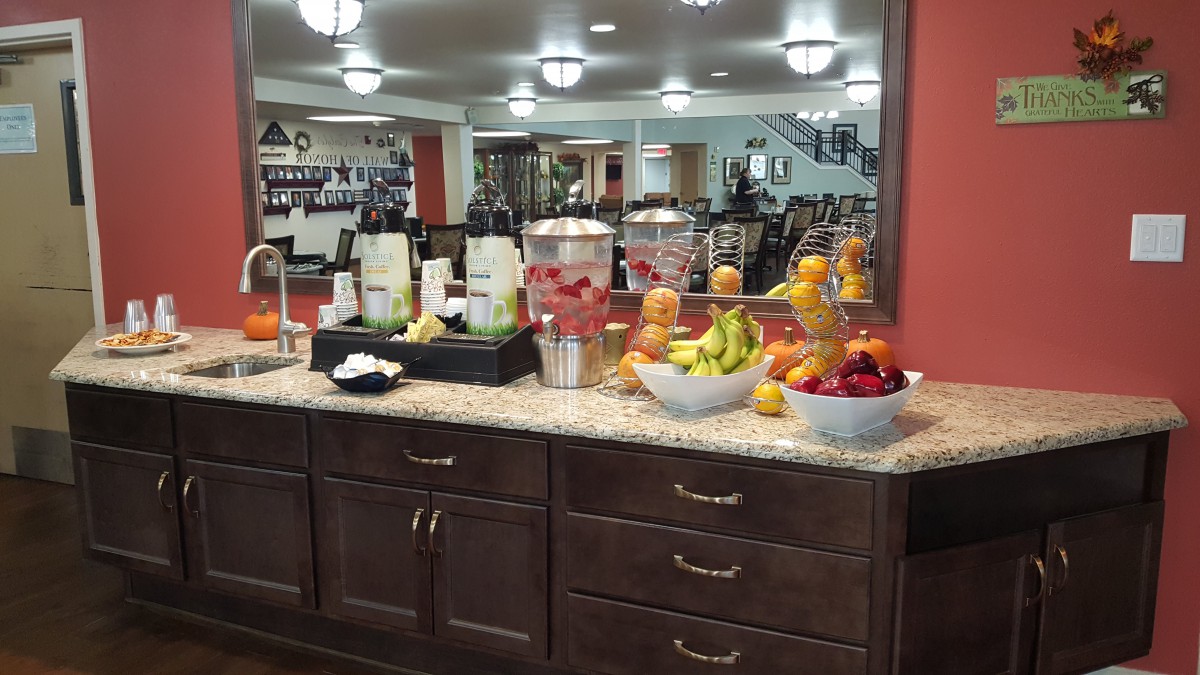 A well-stocked refreshments area in a hotel lobby featuring fresh fruits and beverages.