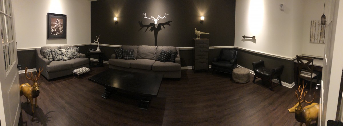 A cozy living room with modern decor featuring a gray sofa, wall-mounted sculpture, and warm lighting.