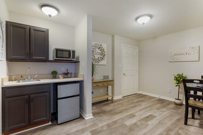 A modern apartment interior with a compact kitchen area, including a microwave and mini fridge.