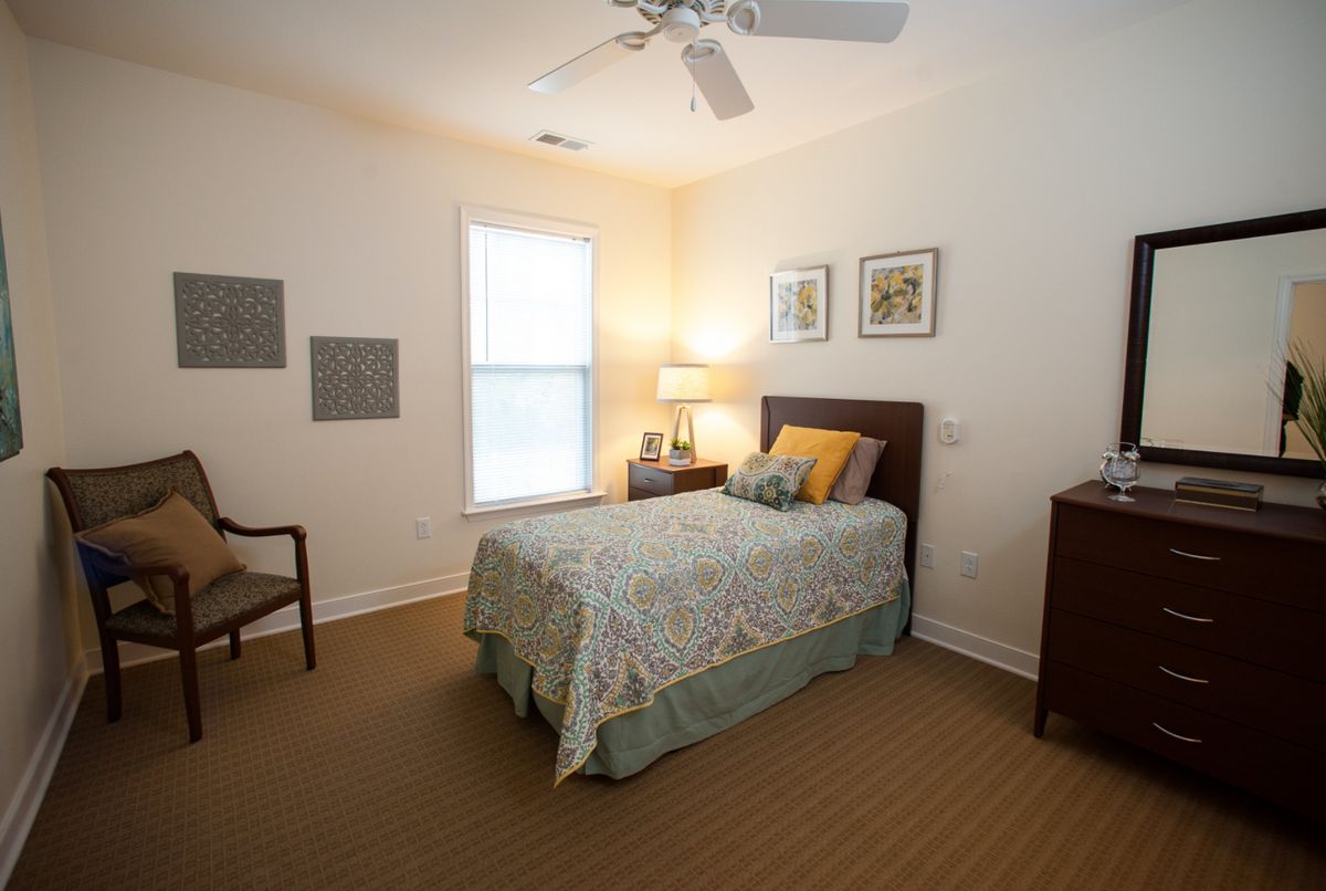 A cozy bedroom with a single bed, a lamp on a nightstand, and decorative elements.