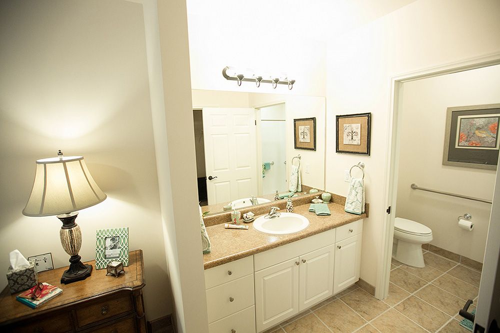 A well-lit bathroom featuring a sink with a countertop, decorative items, and framed pictures on the wall.