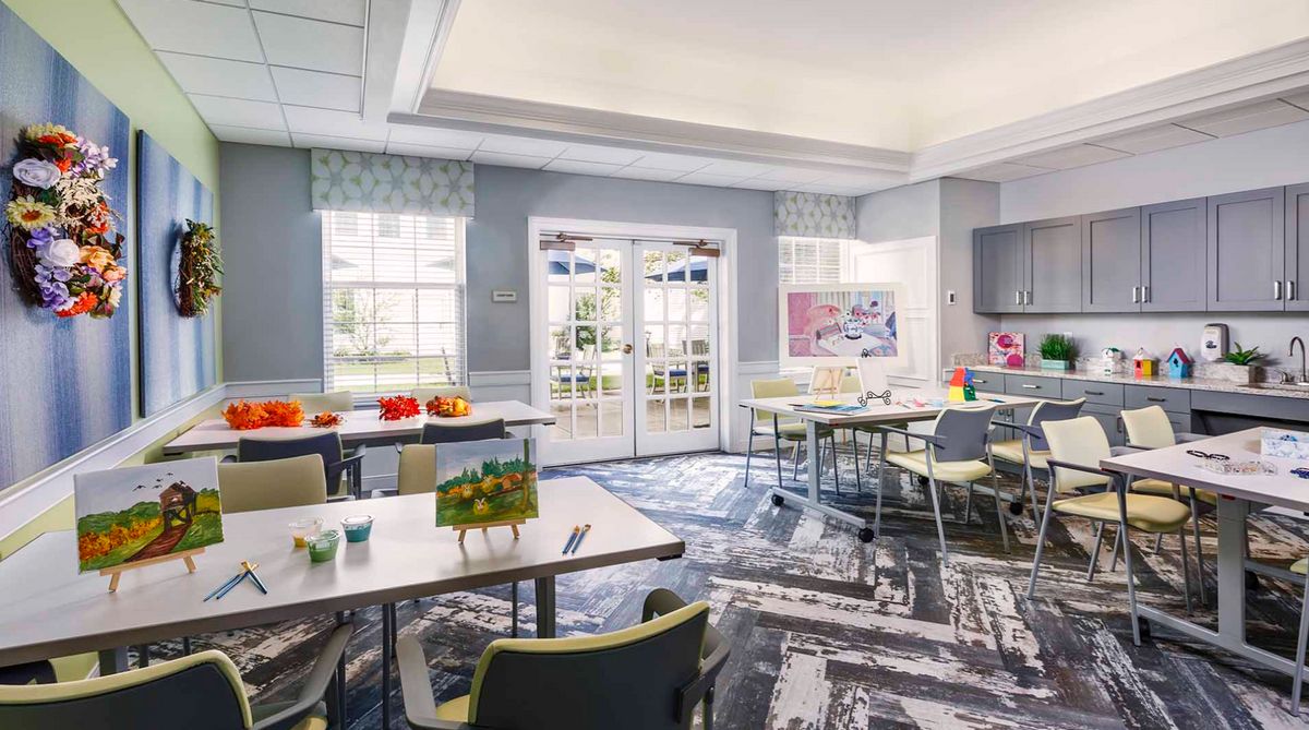 A bright and modern classroom with neatly arranged tables and chairs, large windows, and educational materials.