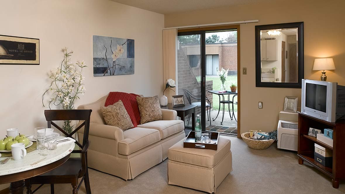 A cozy living room with a sofa, coffee table, and patio doors leading outside.