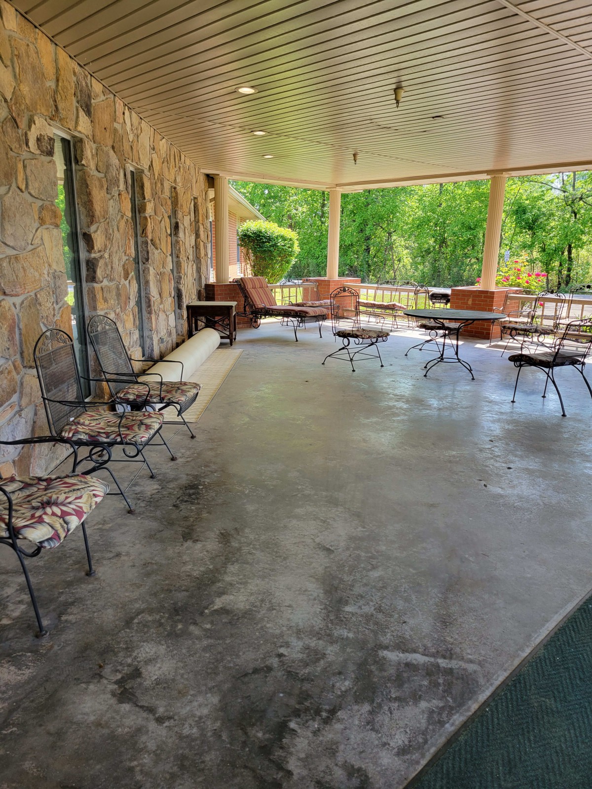A spacious patio with stone walls features outdoor seating arrangements, surrounded by greenery.