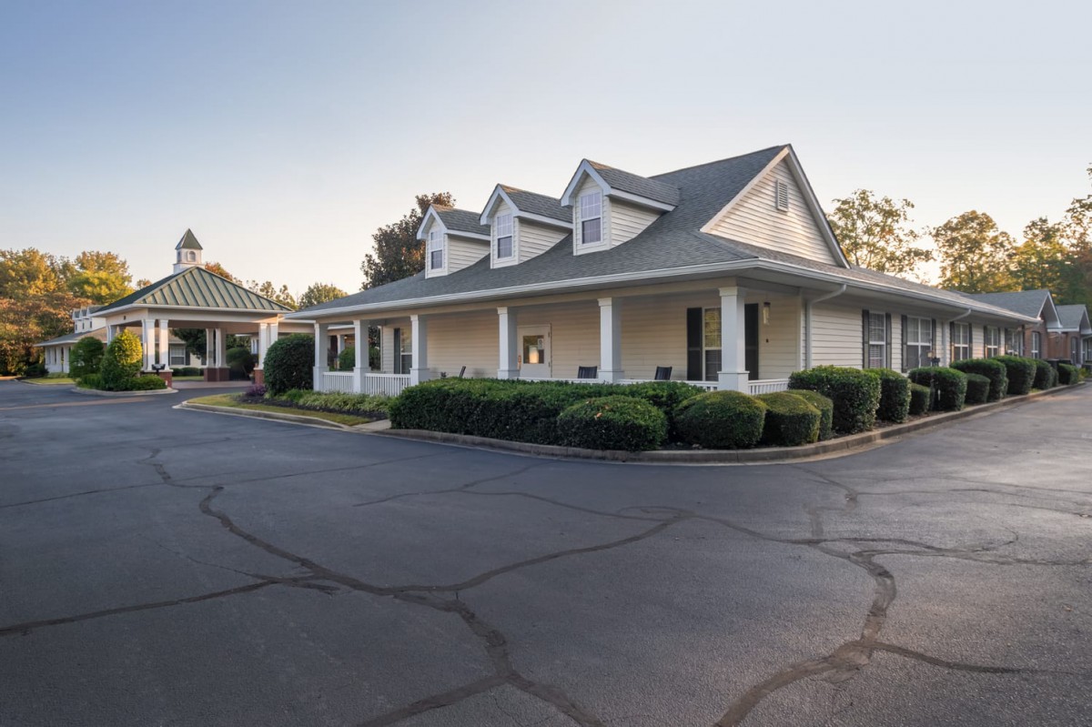 A suburban residential building with a spacious porch and gabled roof.