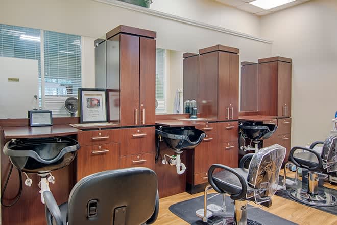 An interior view of a stylish hair salon with wooden cabinets, mirrors, and shampoo stations.