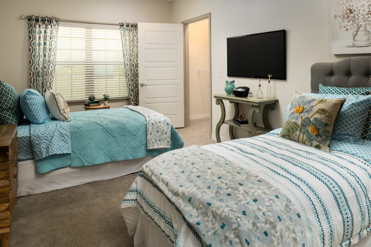 A modern bedroom with twin beds adorned with patterned bedding and a wall-mounted TV.