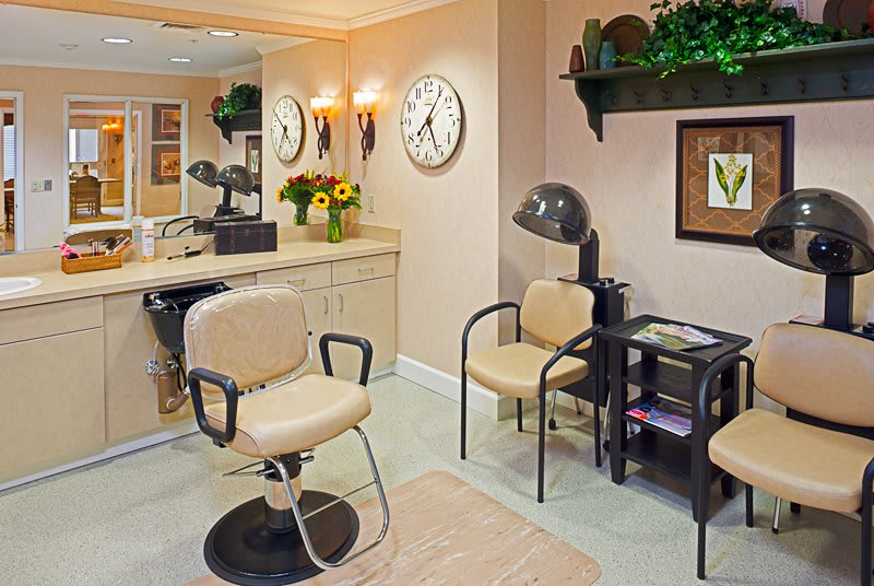 A cozy hair salon interior with chairs and a mirror.