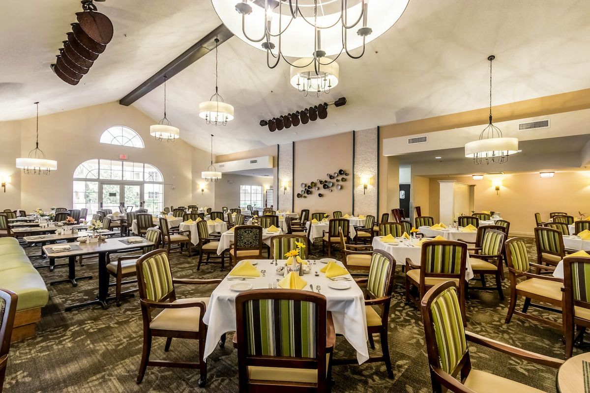 Elegant dining area with chandeliers and neatly arranged tables and chairs.