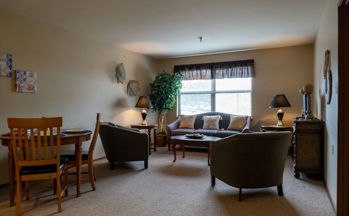 A cozy living room with a sofa, chairs, and a window allowing natural light.
