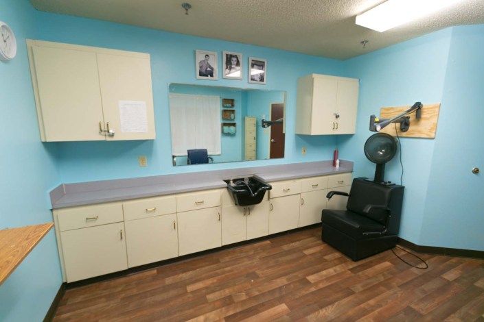 A well-organized hair salon interior with a styling chair, cabinets, and a mirror against blue walls.