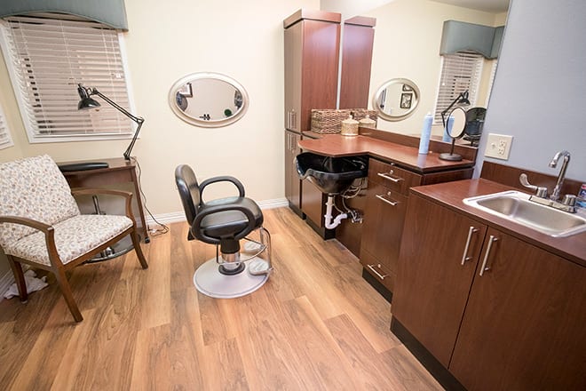 A modern hair salon interior with a styling chair, mirror, and sink.