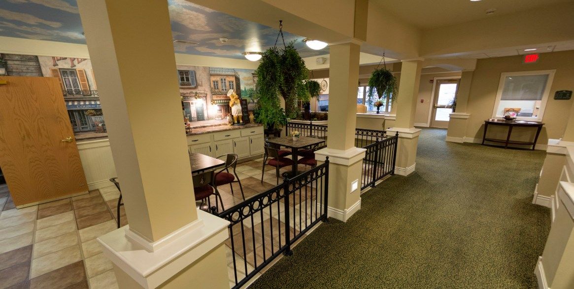 A cozy restaurant interior with tables, chairs, and decorative plants.