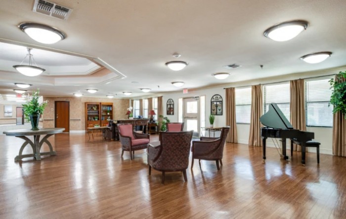 A spacious lounge area with comfortable seating and a piano, featuring wooden floors and warm lighting.