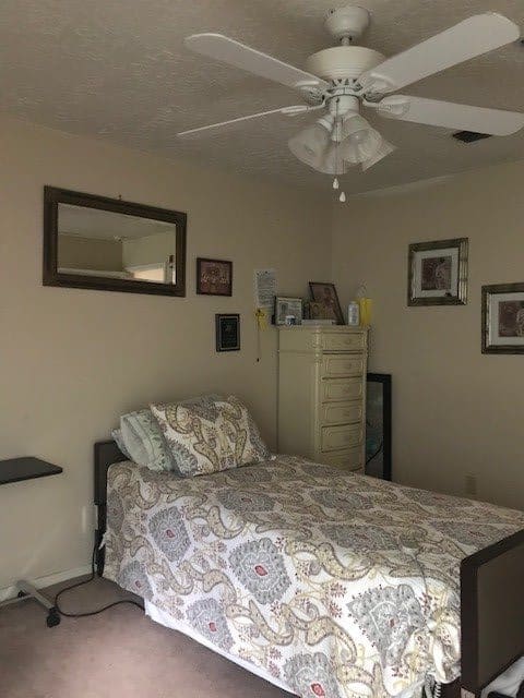 A cozy bedroom with a single bed, mirror, and dresser.