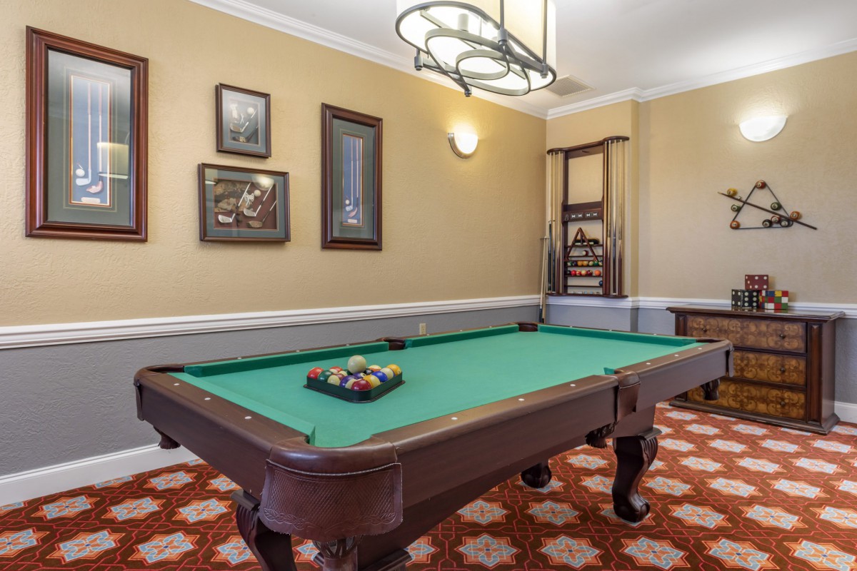A classic billiard room featuring a pool table with decorative wall art.