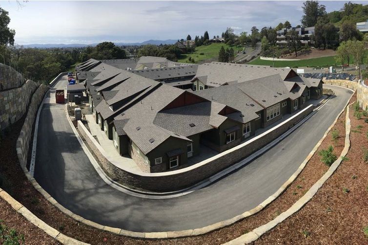 Aerial view of a residential building with multiple rooftops and surrounding roads.