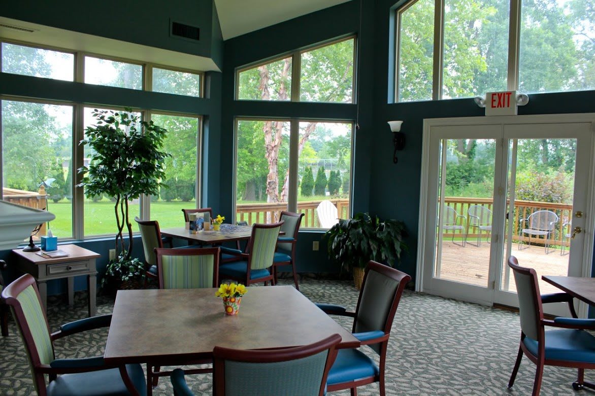 A bright and inviting dining area with large windows overlooking a green outdoor space.