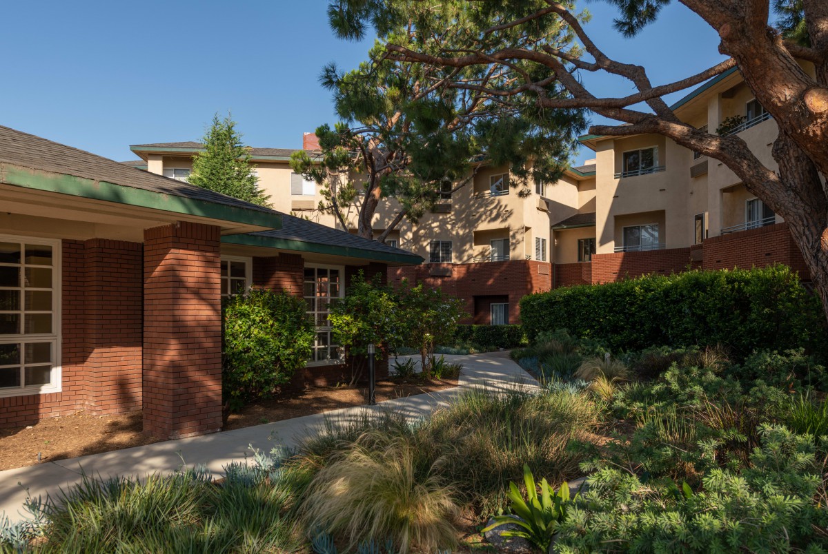 A residential apartment complex surrounded by lush greenery and a clear sky.