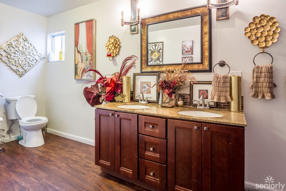 A stylish bathroom with a wooden vanity, adorned with flowers and artwork.
