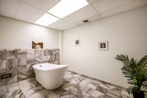 A modern bathroom featuring a stylish bathtub, decorative tiles, and framed artwork.