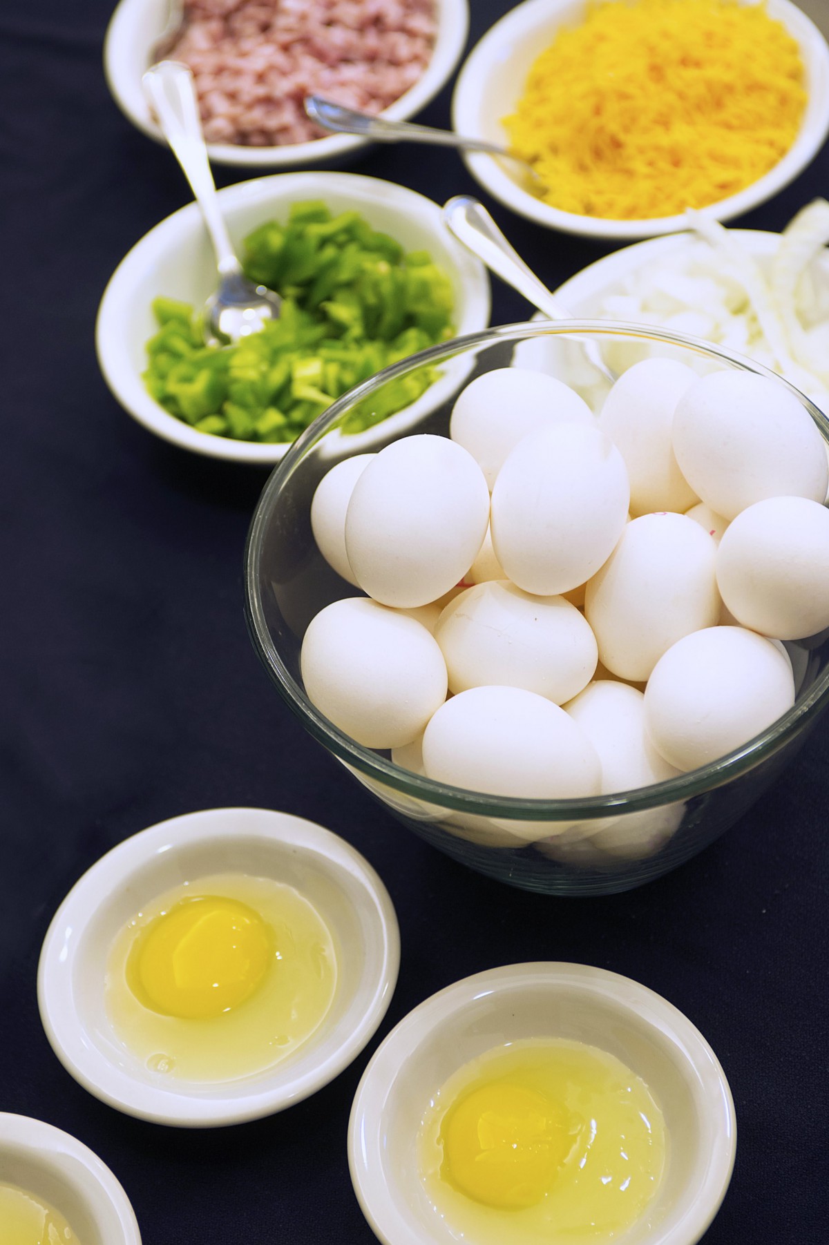 A bowl of eggs surrounded by various cooking ingredients ready for preparation.