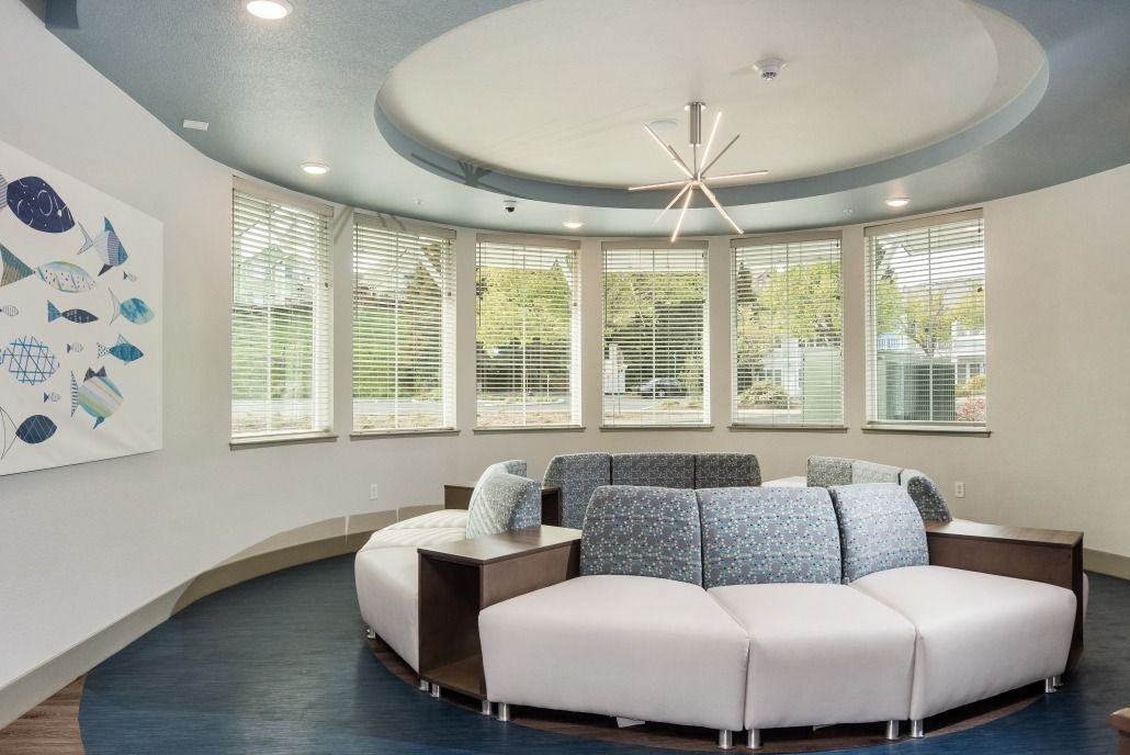 A modern lounge area with a circular sofa and large windows allowing natural light to fill the space.