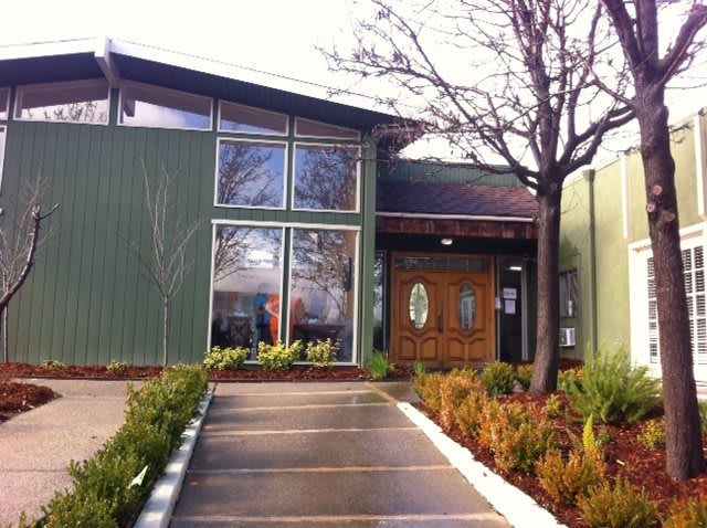 A modern building entrance with landscaped pathways and large glass windows.