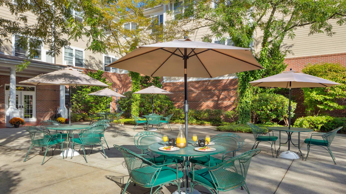 Sunny patio with tables, chairs, and large umbrellas for outdoor relaxation.