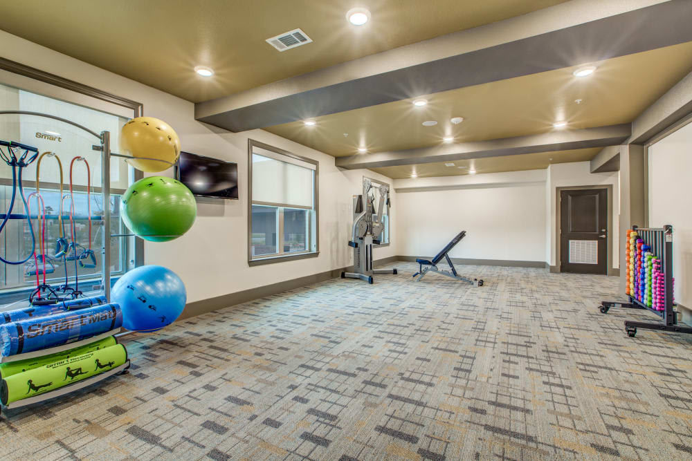 A spacious gym with exercise equipment and colorful yoga balls.