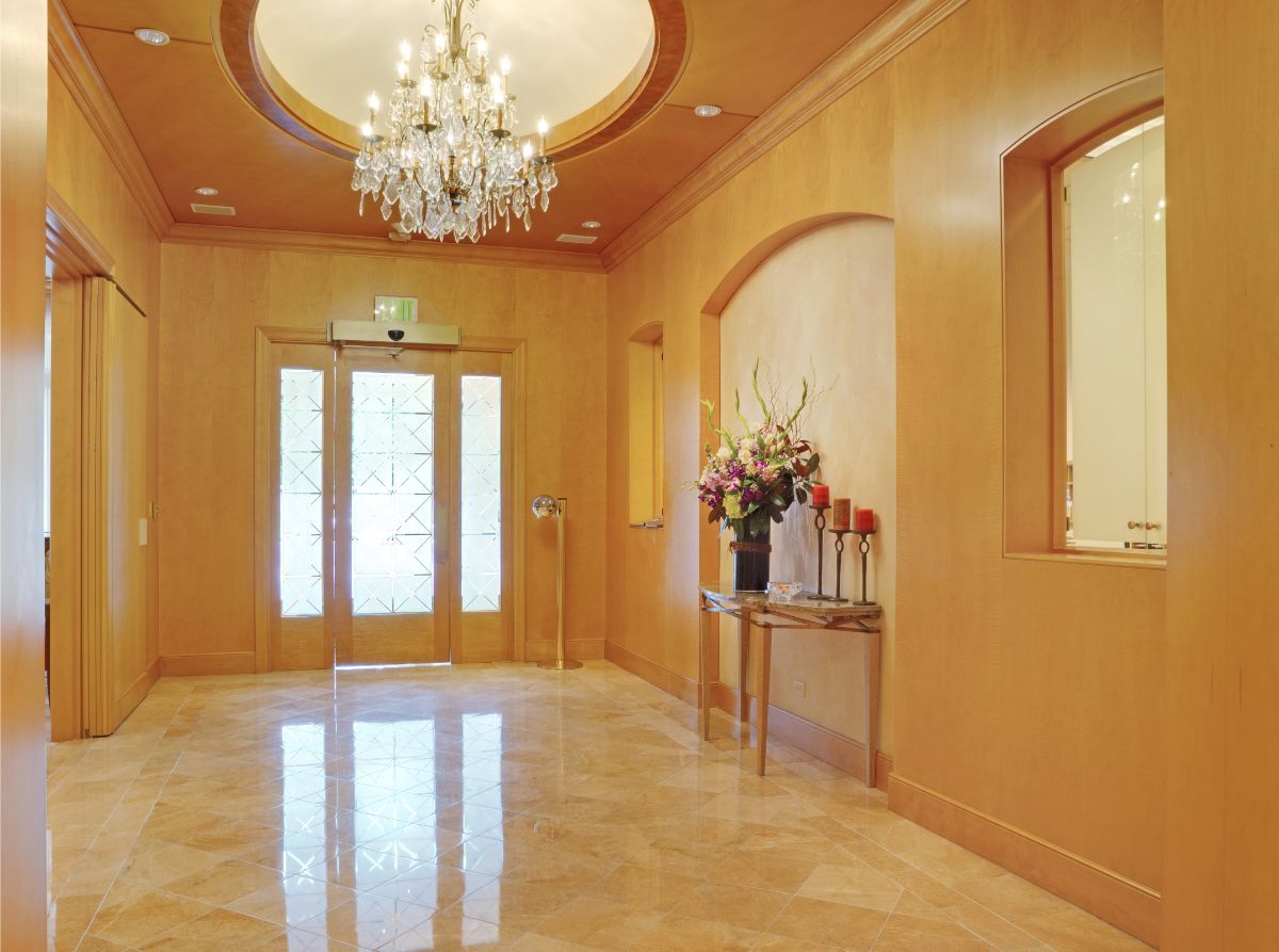 Elegant entrance with a chandelier and floral arrangement.