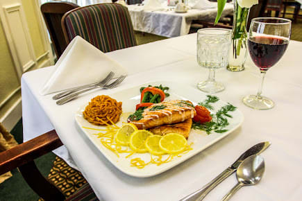 A gourmet plate featuring salmon with lemon slices, a side of pasta, and vegetables elegantly arranged on a restaurant table.