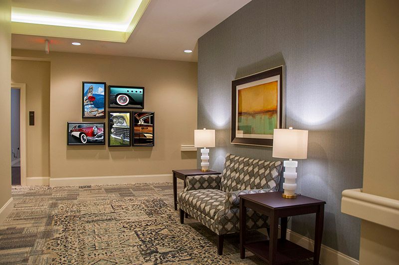 A well-decorated lobby featuring a patterned sofa, side tables with lamps, and various artworks on the walls.