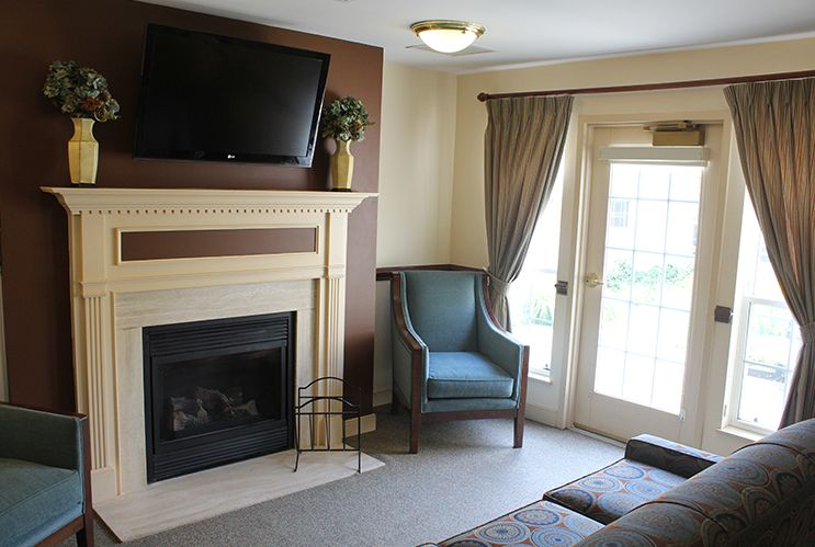 A cozy living room with a fireplace, mounted television, and comfortable seating.
