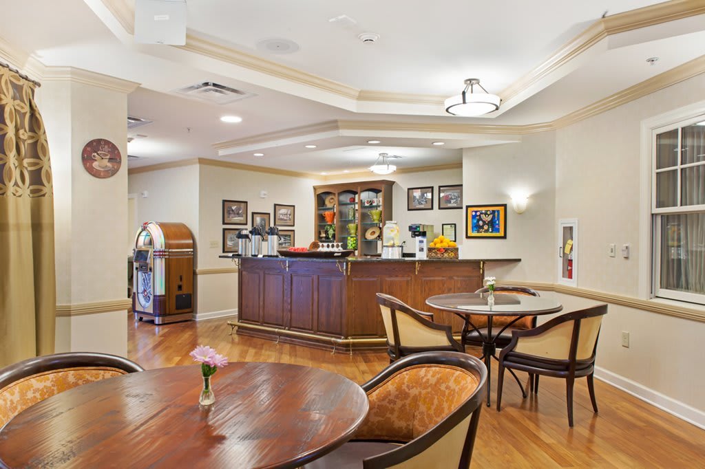 A cozy lounge with a bar, decorated with a jukebox and framed pictures.