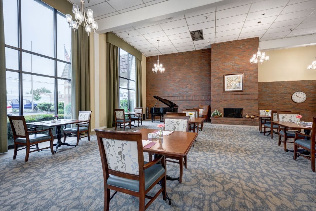 A spacious dining area with tables, chairs, a grand piano, and a fireplace.