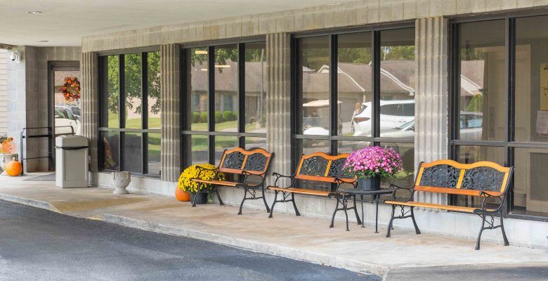 A cozy outdoor seating area with benches and vibrant potted flowers in front of a building.