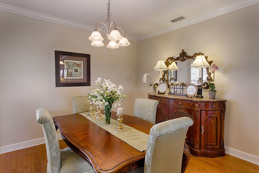 A cozy dining room with a wooden table, cushioned chairs, and a decorative chandelier.