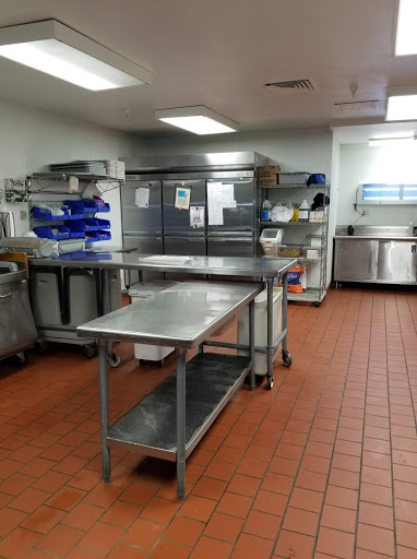 A well-organized commercial kitchen workspace, featuring stainless steel tables and storage units.